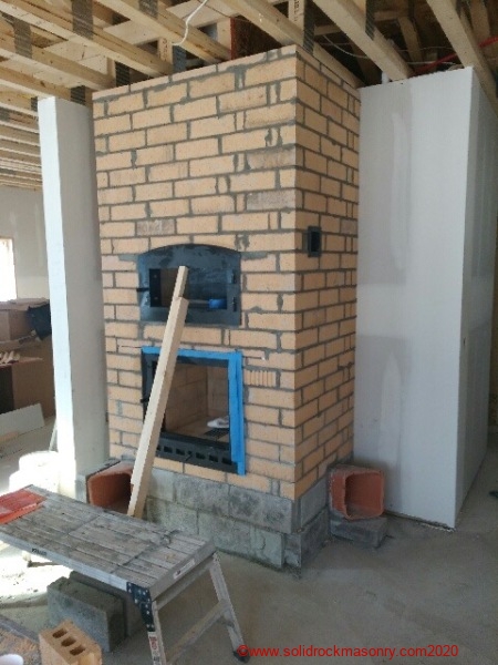 Masonry heater finished with brick for stucco base finish